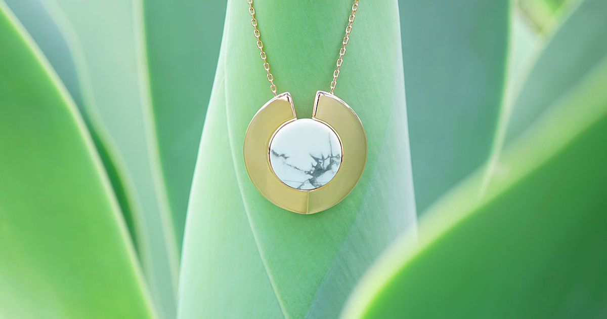 Golden pendant with howlite gemstone on leafy background
